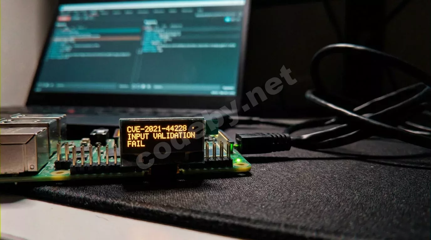 Raspberry Pi с OLED-экраном и янтарным текстом об уязвимости на тёмном антистатическом коврике. На заднем плане ноутбук с Burp Suite в бирюзовом свечении.
